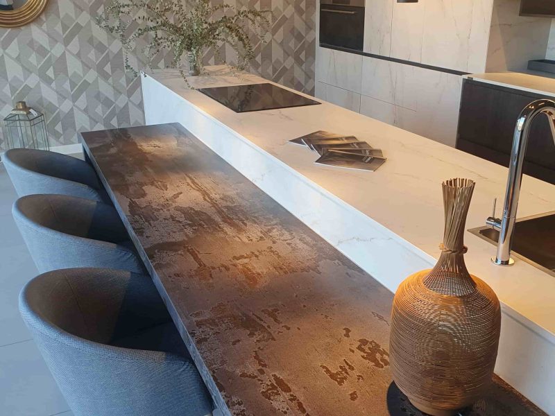 Exposición en el interior de la tienda de una cocinas con muebles blancos y mesa de madera